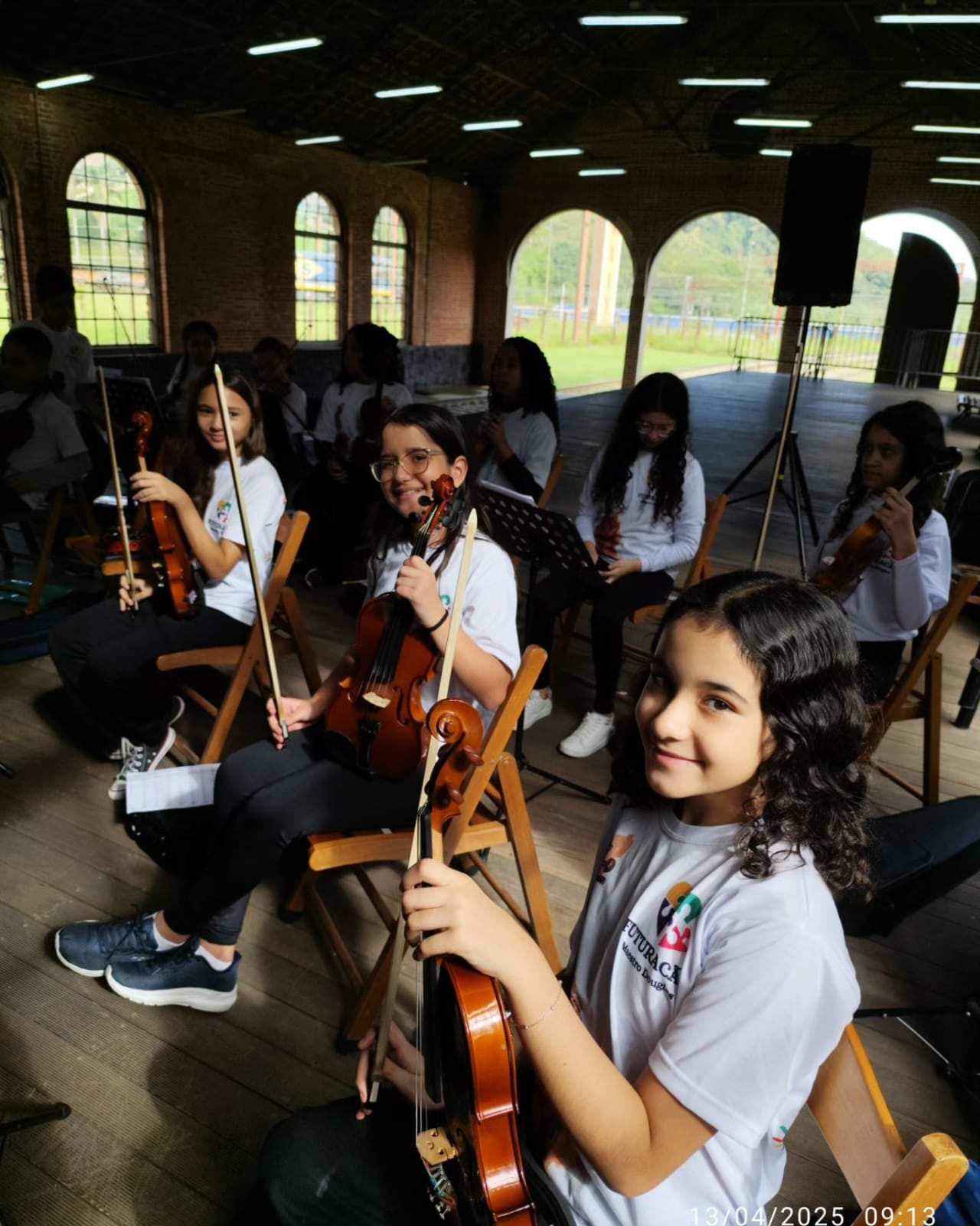 Crianças e adolescentes do projeto Na Trilha do Amanhã tocando violino em ensaio